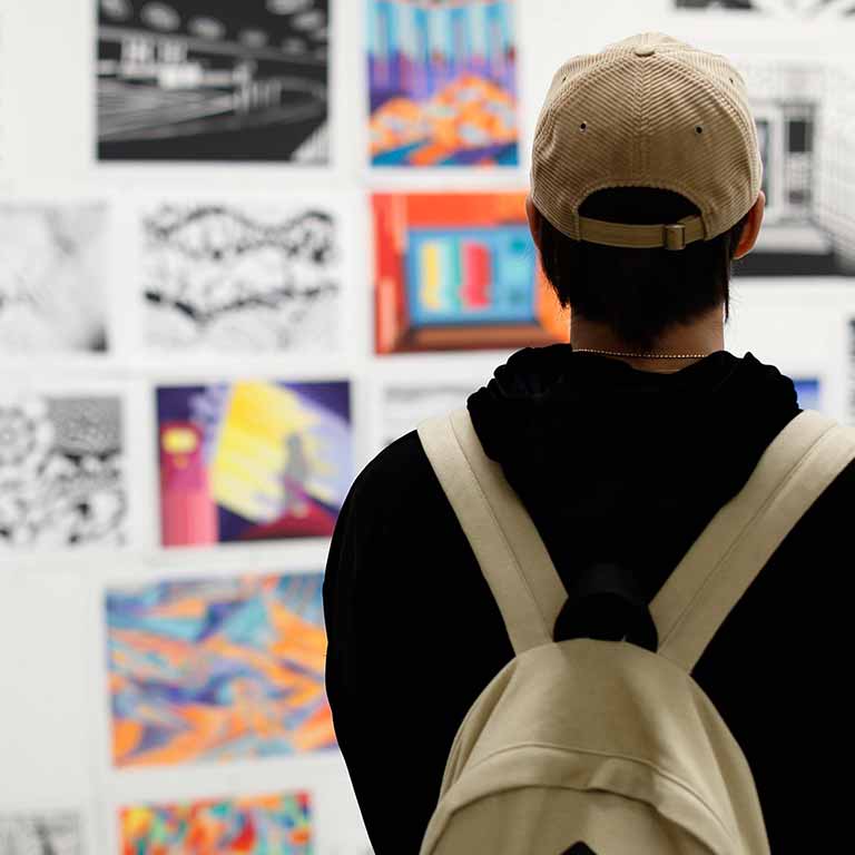 A student looks at drawings on a gallery wall.