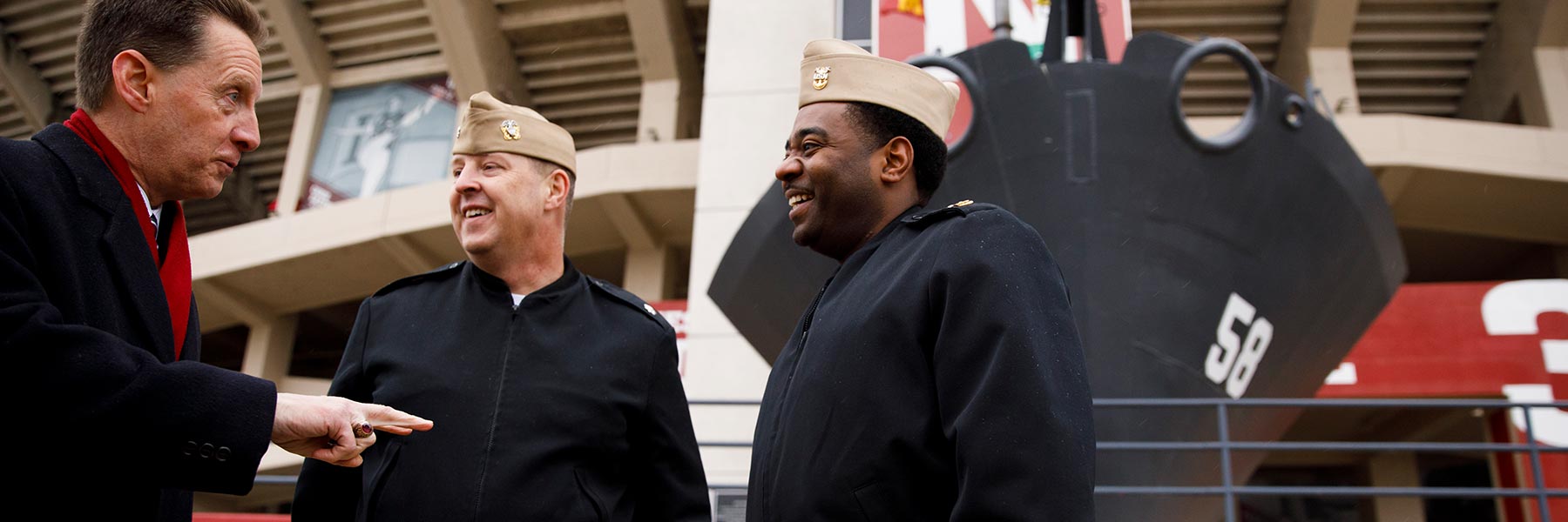 Kirk White talks with members of the U.S. Navy in front of the prow of the U.S.S. Indiana at Memorial Stadium.