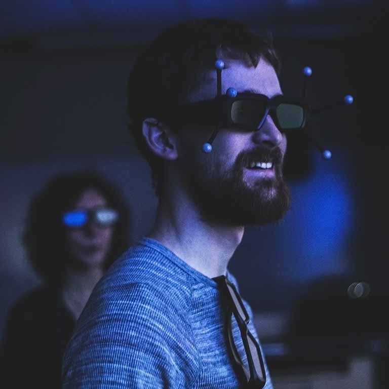 A bearded man wearing 3D glasses looks at something off screen.
